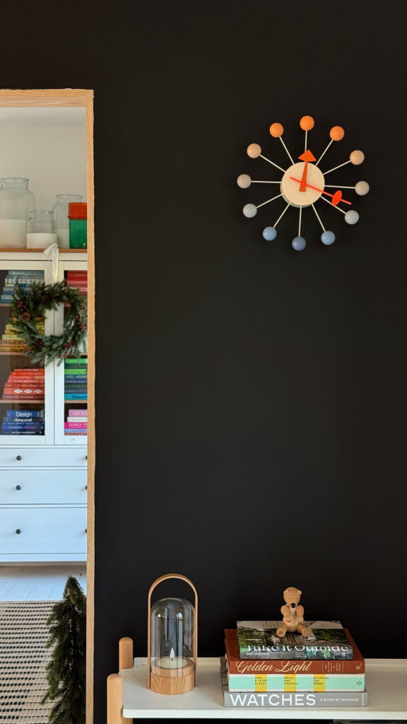 Ball clock multicoloured on a black wall modern design